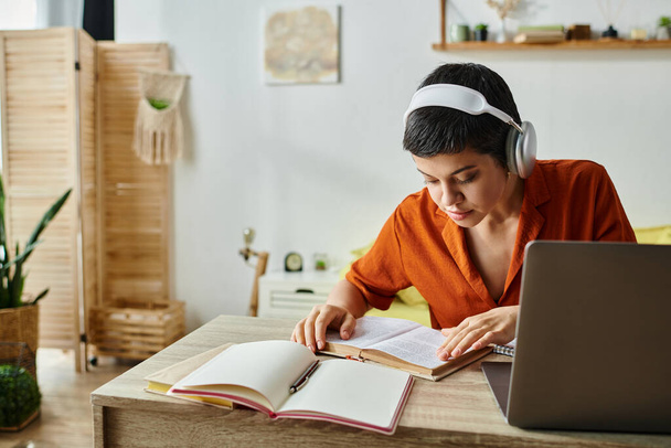 geconcentreerd kortharig vrouw met koptelefoon studeren van thuis uit te kijken naar leerboek, onderwijs - Foto, afbeelding