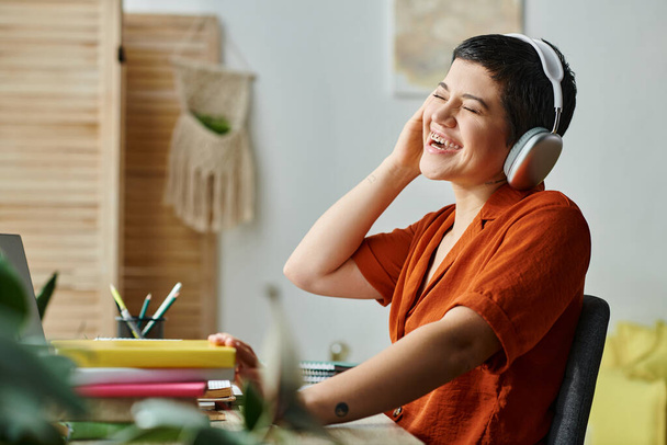 radosna kobieta ze słuchawkami i przeszywającym śmiechem podczas lekcji zdalnej, edukacja w domu - Zdjęcie, obraz