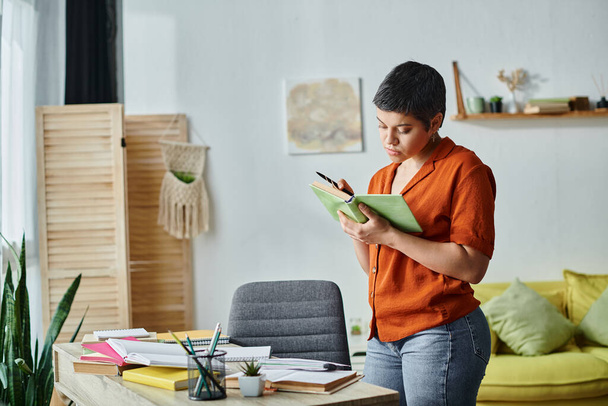 привлекательный трудолюбивый студент, стоящий у стола и внимательно читающий учебники, образование - Фото, изображение