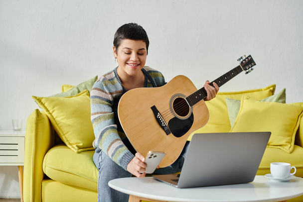 mujer atractiva alegre mirando su teléfono durante la lección de guitarra remota, la educación en casa - Foto, Imagen