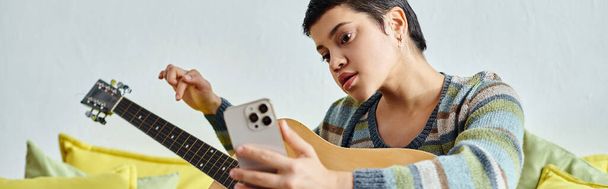 atractiva mujer enfocada que asiste a clases de guitarra en línea con teléfono en las manos, educación, bandera - Foto, Imagen
