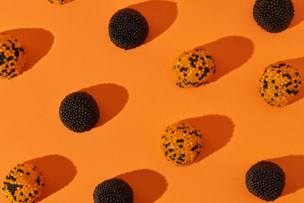 Caramelo sobre fondo naranja. Tarjeta de felicitación de papel pintado de Halloween. Composición creativa en estilo minimalista - Foto, imagen