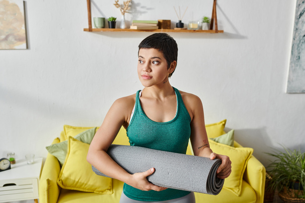 attractive sporty woman with short hair with fitness mat in her living room, fitness and sport - Photo, Image