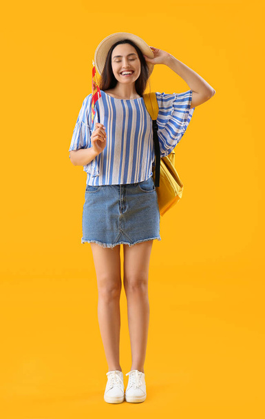 İspanya bayrağı ve sarı arka planda sırt çantası olan genç bir kadın. - Fotoğraf, Görsel