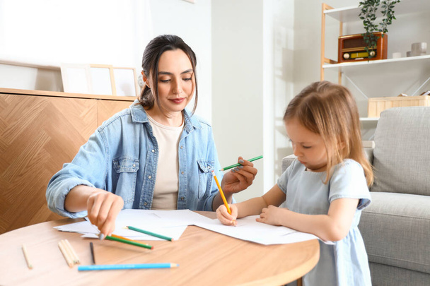 Mujer joven con su hija pequeña dibujando en casa - Foto, imagen