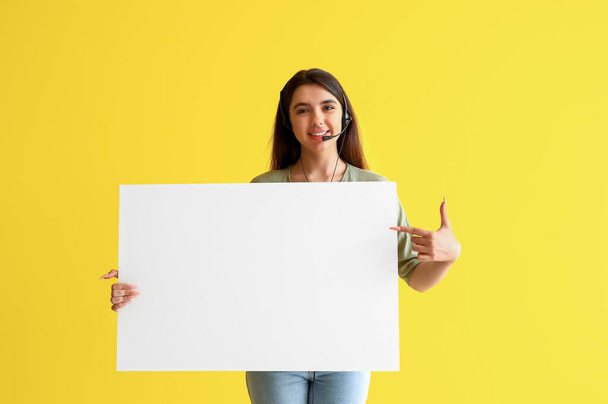 Agente de soporte técnico femenino con póster en blanco sobre fondo amarillo - Foto, imagen