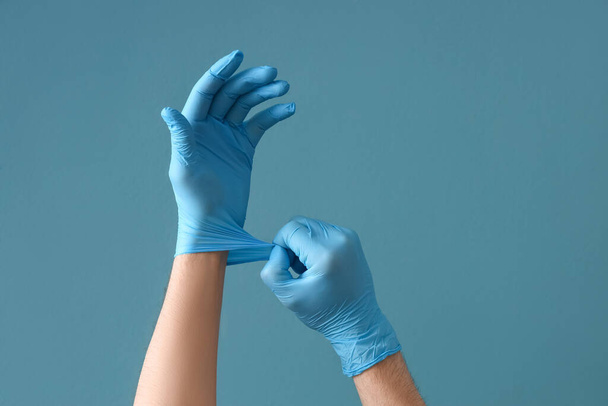 Доктор надевает резиновые перчатки на синий фон - Фото, изображение