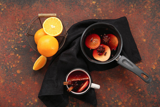Saucepan i filiżanka gorącego grzanego wina z pomarańczą na ciemnym tle - Zdjęcie, obraz