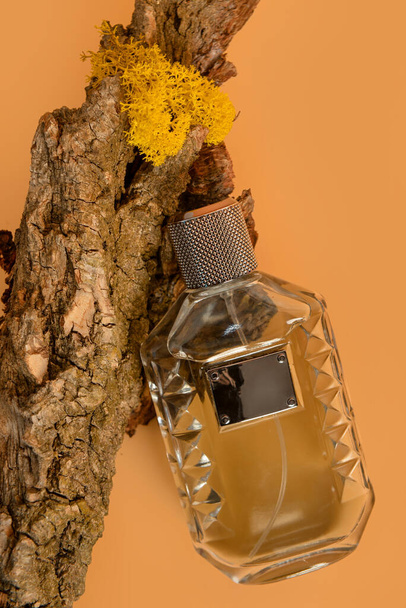 Пляшка парфумів і кори дерева на помаранчевому фоні - Фото, зображення