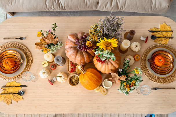 Autumn setting with pumpkins and flowers on dining table in room, top view - Photo, Image