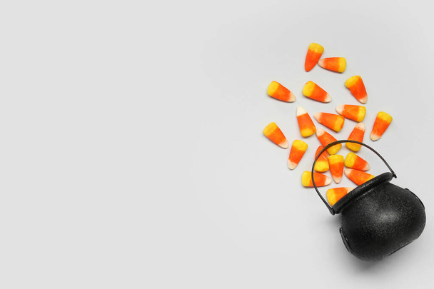 Composición de Halloween con caldero volcado y granos de caramelo sobre fondo gris - Foto, Imagen