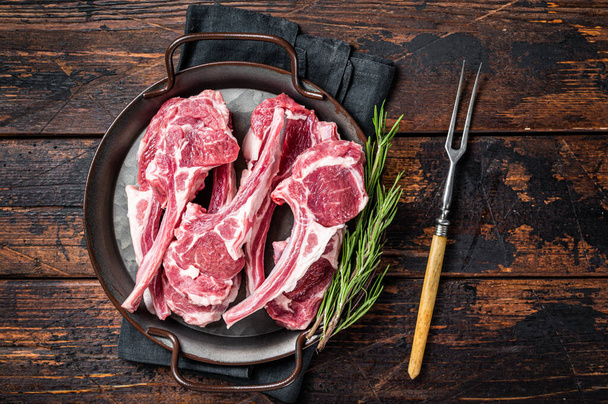 Raw lamb mutton chop steaks, fresh meat cutlets on butcher table. Black background. Top view. - Foto, Bild