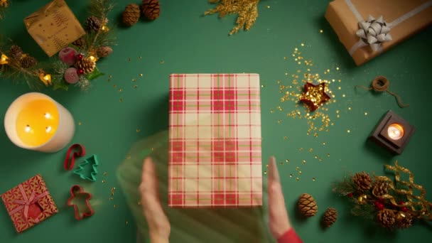 Montón de arriba hacia abajo de cajas de regalo de Navidad coloridas colocadas una por una con anillo de compromiso colocado en la parte superior. Las manos femeninas y masculinas ponen muchas cajas de regalo coloridas en la mesa verde con decoraciones de Navidad - Metraje, vídeo