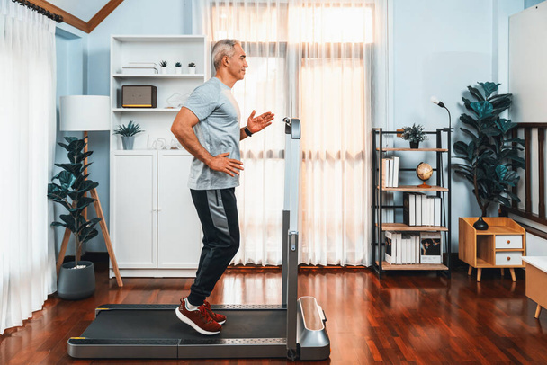 Aktív idős férfi fut futófelület futógépen otthon együtt teljes test lövés, mint a fitness egészséges életmód és a testápolás után nyugdíjas. Kömény - Fotó, kép
