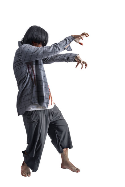A scary zombie with blood and wounds on his body walking isolated over a white background - 写真・画像