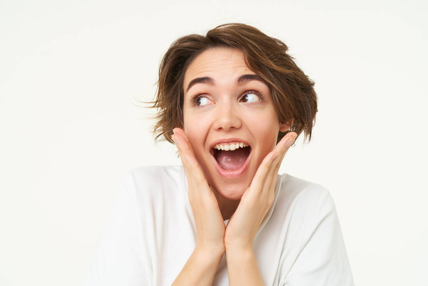 Fantastic news. Portrait of amazed young woman, looks surprised, gasps impressed, stands over white background. - Photo, Image