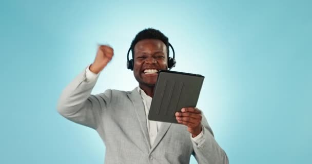 Homem negro feliz, tablet e call center em celebração, ganhando ou boas notícias contra um fundo de estúdio azul. Empresário africano entusiasmado, consultor ou agente dançando com tecnologia para realização. - Filmagem, Vídeo