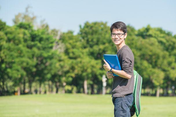 Asijská studentka drží knihy a usmívá se, když stál v parku - Fotografie, Obrázek