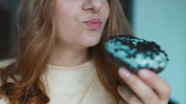 Close up portrait of a hungry 30s woman eating donuts with white frosting.Girl sniffs sweet pastries. Eating donut when takeout and delivery. Fast food takeaway back home. High quality FullHD footage - Footage, Video