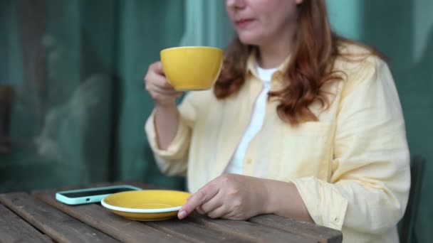 Nahaufnahme einer jungen schönen, glücklichen Frau, die in einem Straßencafé Cappuccino genießt. Weibliche Hände halten eine Tasse Kaffeetasse mit herzförmigem Latte-Art-Schaum. Hochwertiges FullHD-Filmmaterial - Filmmaterial, Video