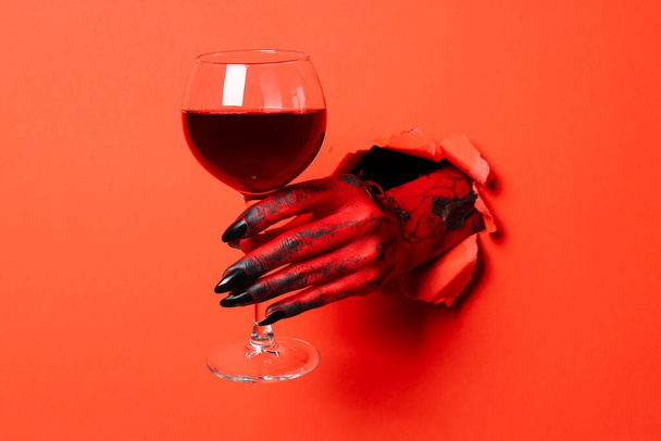 Mano rossa femminile con bicchiere di vino su sfondo rosso - Foto, immagini
