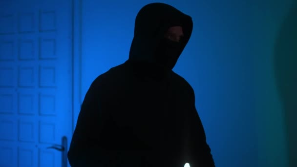 Грабитель в маске с фонариком проверяет квартиру. - Кадры, видео
