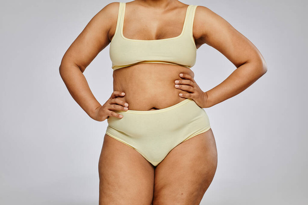 Minimal cropped shot of unrecognizable black woman wearing underwear against grey background, body positivity - Foto, Imagem