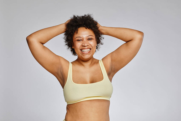 Minimal waist up portrait of carefree black woman wearing underwear and laughing happily against grey background - Фото, зображення