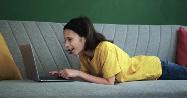 In the inviting living room, a boy engrossed in his laptop, and bursts into laughter. His infectious joy fills the room, combining digital entertainment with genuine amusement in a heartwarming scene. - Footage, Video