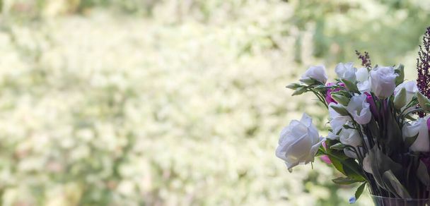Une partie du bouquet de roses blanches et d'eustomes situé à droite sur un fond vert clair flou, panorama avec le centre vide et la partie gauche - Photo, image