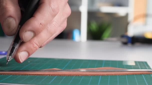 handgefertigtes Produkt, ein Mann mit Stift und Lineal misst die Länge, um die Ledertasche zu schneiden, Nahaufnahme - Filmmaterial, Video