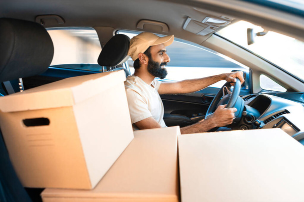 Delivery. Indian Courier Man Driving Car Loaded With Big Carton Boxes Shipping Parcels From Online Store To Customers, Sitting Driver Seat In Automobile Inside. Side View, Selective Focus - Photo, Image