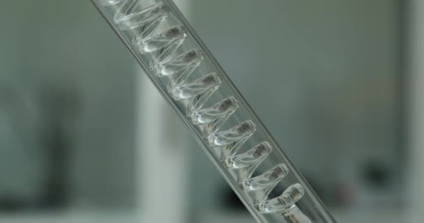 Przezroczysta substancja płynna przepływa przez kolbę ze szkła spiralnego. Fiolka szklana i filtracja płynności - Materiał filmowy, wideo