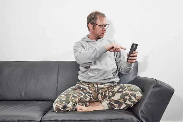 Mann mit Brille zu Hause mit Handy - Foto, Bild