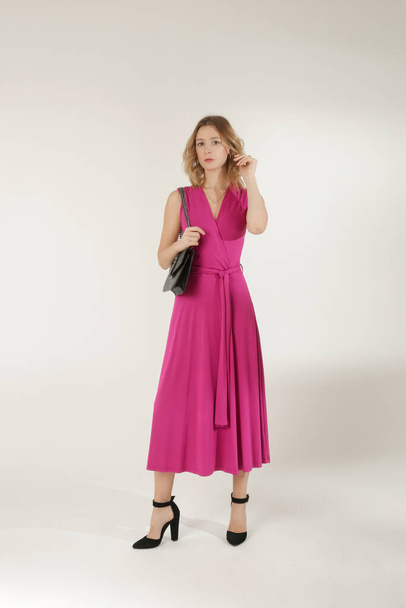 ピンクのビスコースラップドレスの若い女性モデルのスタジオ写真のセリエ. - 写真・画像
