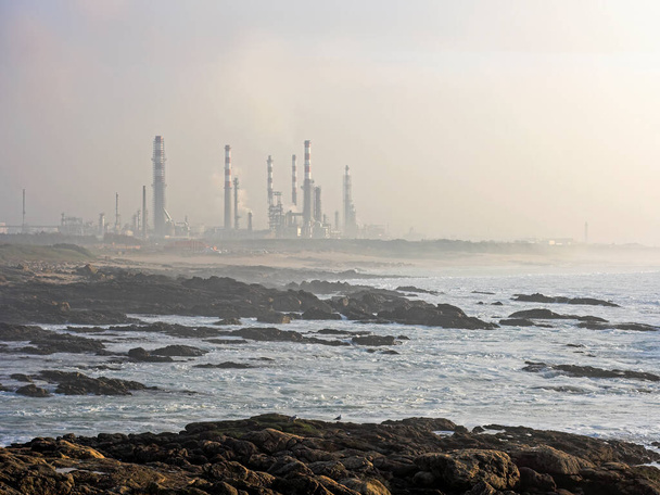 Нефтеперерабатывающий завод у моря в таинственный вечер - Фото, изображение