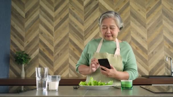 Una mujer asiática feliz y saludable toma una foto y VLOG su comida después de cocinar por la mañana para publicar en las redes sociales, el disfrute de las personas mayores activas y la actividad después de la jubilación, jubilado seguro. - Metraje, vídeo