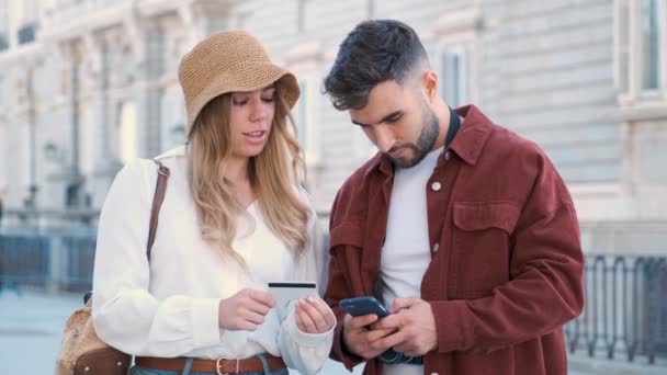 Mladý bělošský pár kupující vstupenky s kreditní kartou a telefonem k návštěvě Madridu, Španělsko. - Záběry, video
