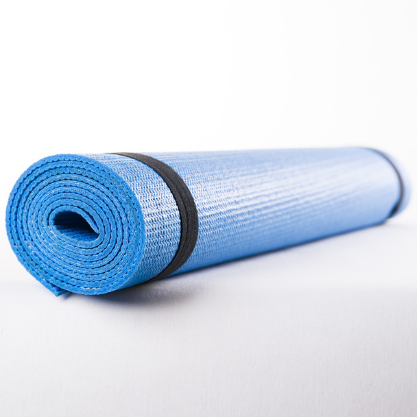 Blauwe mat voor fitness op een witte achtergrond. - Foto, afbeelding