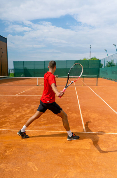 Jungprofi-Spielertrainer übt auf Tennisplatz Schläge mit Schläger-Tennisball - Foto, Bild