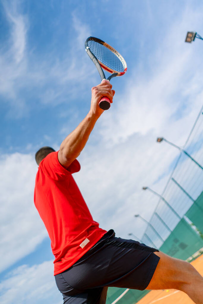 young professional player coach on outdoor tennis court practices strokes with racket tennis ball - Photo, Image