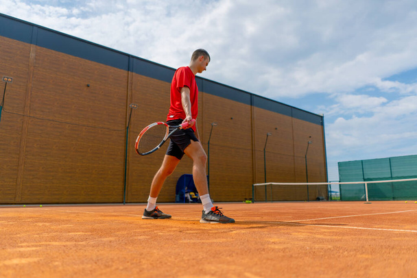 fiatal profi játékos edző szabadtéri teniszpálya gyakorló stroke ütő és tenisz labda ellen játszik ellenfél - Fotó, kép