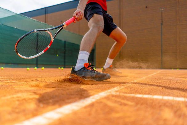 primer plano del pie de un jugador de tenis o instructor en el polvo de tierra de la cancha al aire libre que se levanta cerca del zapato - Foto, Imagen
