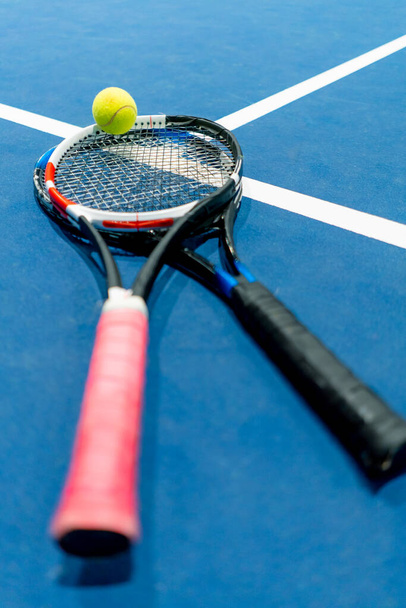 lähikuva urheiluvälineet tennis pallo ja maila sijaitsevat sisätiloissa ammatillinen sininen tuomioistuin harrastus kilpailu urheilu - Valokuva, kuva