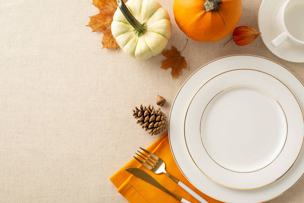 Arreglo de mesa inspirado en el otoño: Platos de exhibición de vista superior, taza, cubiertos, servilleta naranja. Adornado con calabazas, hojas de arce, y más en suave mantel beige. Perfecto para mensajes o anuncios estacionales - Foto, Imagen