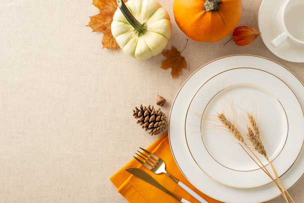Harvest-themed tabletop setting: Top view of plates, cup, cutlery, orange napkin. Embellished with pumpkin, pattypan, wheat, seasonal items on pastel beige tablecloth. Empty area for text or ad - Photo, Image