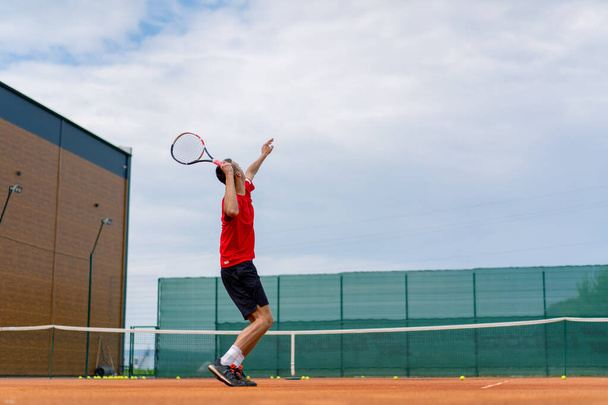 young professional player coach on outdoor tennis court practices strokes with racket tennis ball - Photo, Image