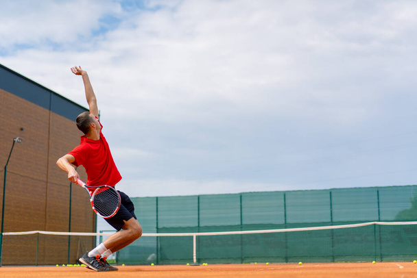mladý profesionální hráč trenér na venkovním tenisovém kurtu cvičí tahy s raketový tenisový míček - Fotografie, Obrázek
