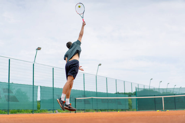 молодий професійний тренер на відкритому повітрі тенісний корт практикує інсульти з ракетним тенісним м'ячем - Фото, зображення
