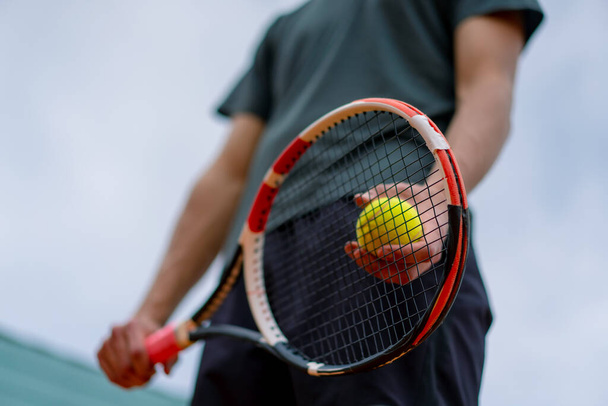 młody trener lub zawodnik trzymający rakietę tenisową i piłkę podczas gry na korcie zbliżenie - Zdjęcie, obraz